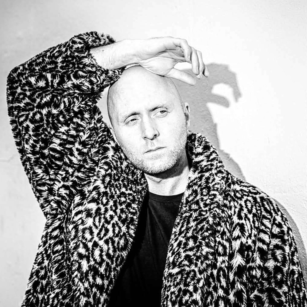 Ísak Morris press photo: black-and-white portrait in a leopard-print coat, arm over his head